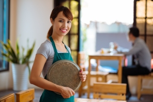 Portrait of Vietnamese beautiful waitress with a tray standing in a cafe